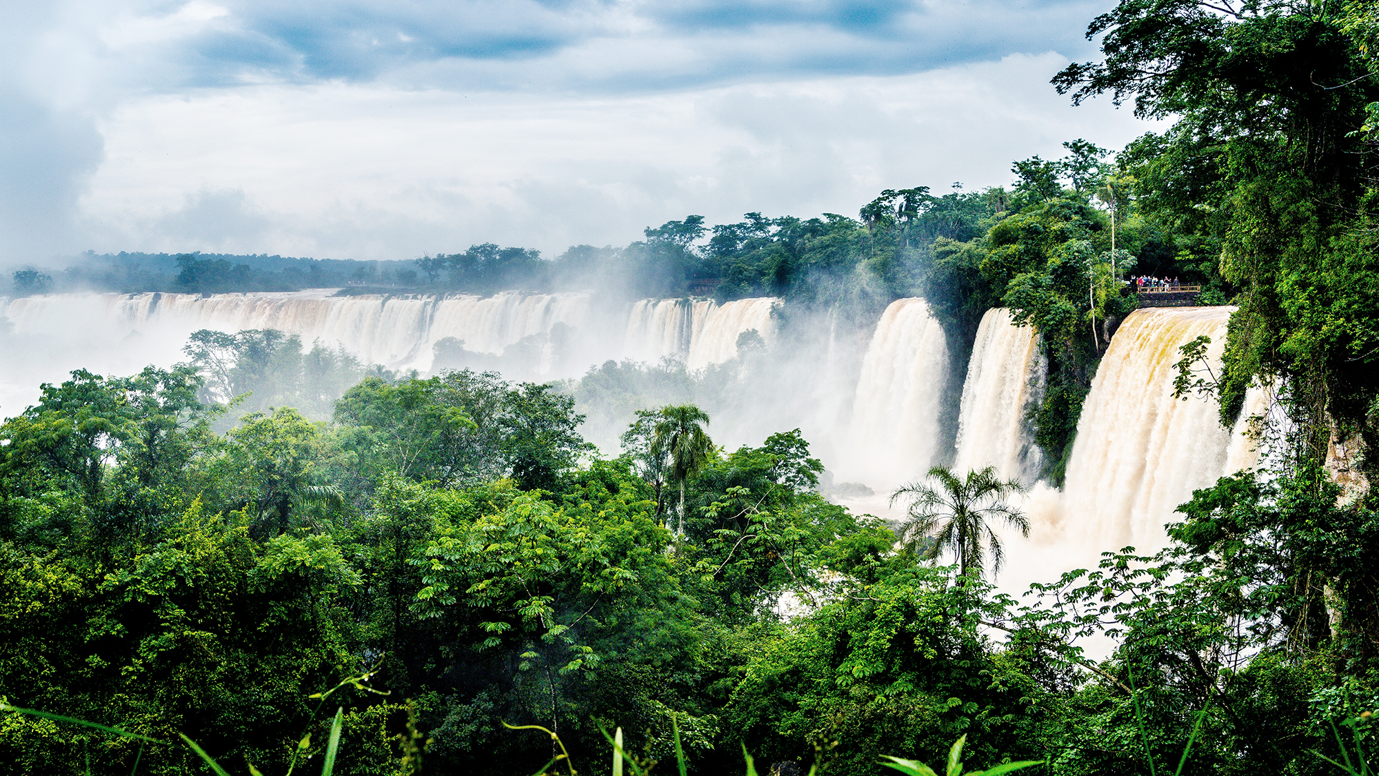 The waterfall at Iguazu National Park surrounded by forests covered in the fog under a cloudy sky